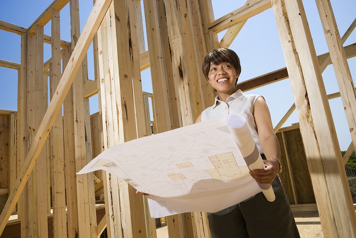 Image of a lady looking at blue prints on a construction site